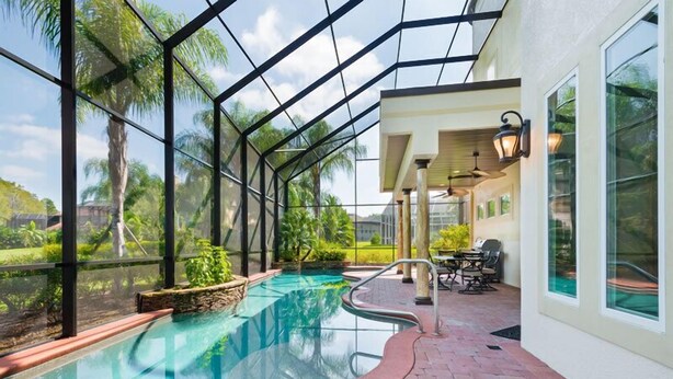 An indoor swimming pool with a glass ceiling, surrounded by plants and a patio area with outdoor seating. - Ov3978 - Formosa Gardens - 7 Bed 7.5 Baths Villa (Kissimmee)