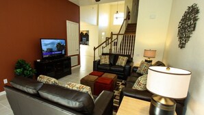 A living room with a TV, leather sofa, coffee table, and a lamp. - Ov4195 - Windsor Hills Resort - 5 Bed 5 Baths Villa (Kissimmee)