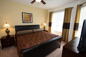 A hotel room with a bed, two bedside tables with lamps, a ceiling fan, a framed picture on the wall, and a window with curtains. - Ov4195 - Windsor Hills Resort - 5 Bed 5 Baths Villa (Kissimmee)
