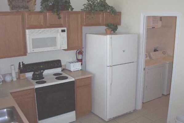 A compact kitchen with a stove, microwave, and refrigerator.
