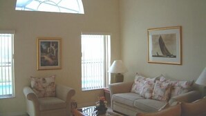 Ein Wohnzimmer mit zwei Sofas, einer Lampe und zwei gerahmten Bildern an der Wand.