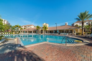 A swimming pool with lounge chairs and umbrellas, surrounded by palm trees and buildings. - Ov4121 - Vista Cay Resort - 3 Bed 2 Baths Condo (Orlando)