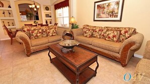 Una sala de estar con un sofá, una mesa de centro y una zona de comedor con sillas y una mesa.