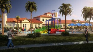 Ein Spielplatz mit bunten Geräten, Palmen und einem Poolbereich mit Sonnenschirmen.