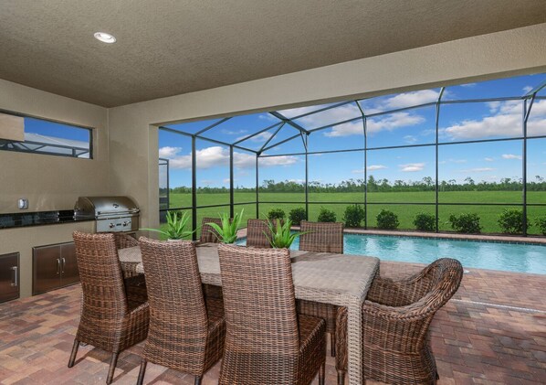 A patio area with a pool, wicker furniture, and a grill.