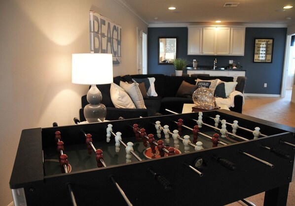 A living room with a foosball table, a sofa, and a lamp.