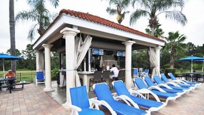 Un espacio de descanso techado al aire libre con sillones reclinables azules y un quiosco.