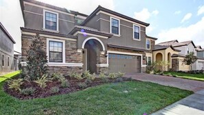A two-story house with a stone facade, a garage, and a well-maintained lawn. - Ov3992 - Champions Gate Resort - 8 Bed 5 Baths Villa (Davenport)