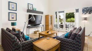 Ein Wohnzimmer mit einer Sofagarnitur, einem Fernseher, einem Couchtisch und einem Schrank.