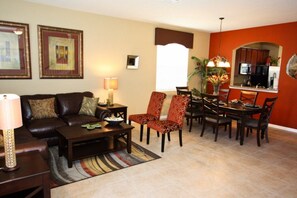 Una sala de estar con un sofá, sillones, una mesa de centro y un comedor con sillas y una mesa.