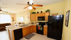 A compact kitchen with wooden cabinets, a black refrigerator, a microwave, and a dishwasher. - Ov4200 - Windsor Hills Resort - 3 Bed 3 Baths Villa (Kissimmee)