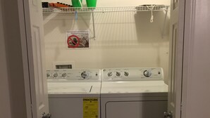 A laundry area with two washing machines, a drying rack, and a basket.