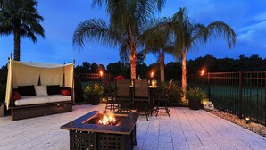 Un patio al aire libre con un pozo de fuego, asientos y palmeras.