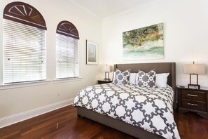 A bedroom with a large bed, two bedside tables, a nightstand, a painting on the wall, and a window with blinds. - Ov4211 - Reunion Resort - 7 Bed 7.5 Baths Villa (Kissimmee)