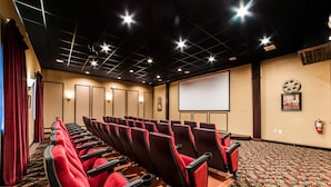 A conference room with rows of red chairs, a projector screen, and a patterned carpet. - Ov4256 - Paradise Palms - 5 Bed 4 Baths Townhome (Kissimmee)