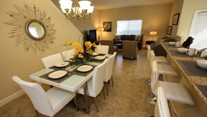 A dining area with a table set for four, a chandelier, and a decorative mirror on the wall. - Ov4256 - Paradise Palms - 5 Bed 4 Baths Townhome (Kissimmee)