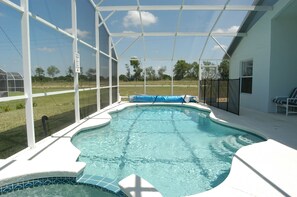 A swimming pool with a glass enclosure, surrounded by a white deck and a covered area with chairs. - Ov3783 - Westbury - 4 Bed 3 Baths Villa (Davenport)
