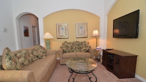 A living room with two sofas, a glass coffee table, a TV, and framed pictures on the wall. - Ov3786 - Cumbrian Lakes - 4 Bed 3.5 Baths Villa (Kissimmee)