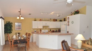 A compact kitchen with white cabinets, a central island, and a dining area with a table and chairs. - Ov3786 - Cumbrian Lakes - 4 Bed 3.5 Baths Villa (Kissimmee)