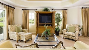 A living room with a television, two armchairs, a coffee table, and a ceiling fan. - Ov4238 - Reunion Resort - 3 Bed 3 Baths Condo (Kissimmee)