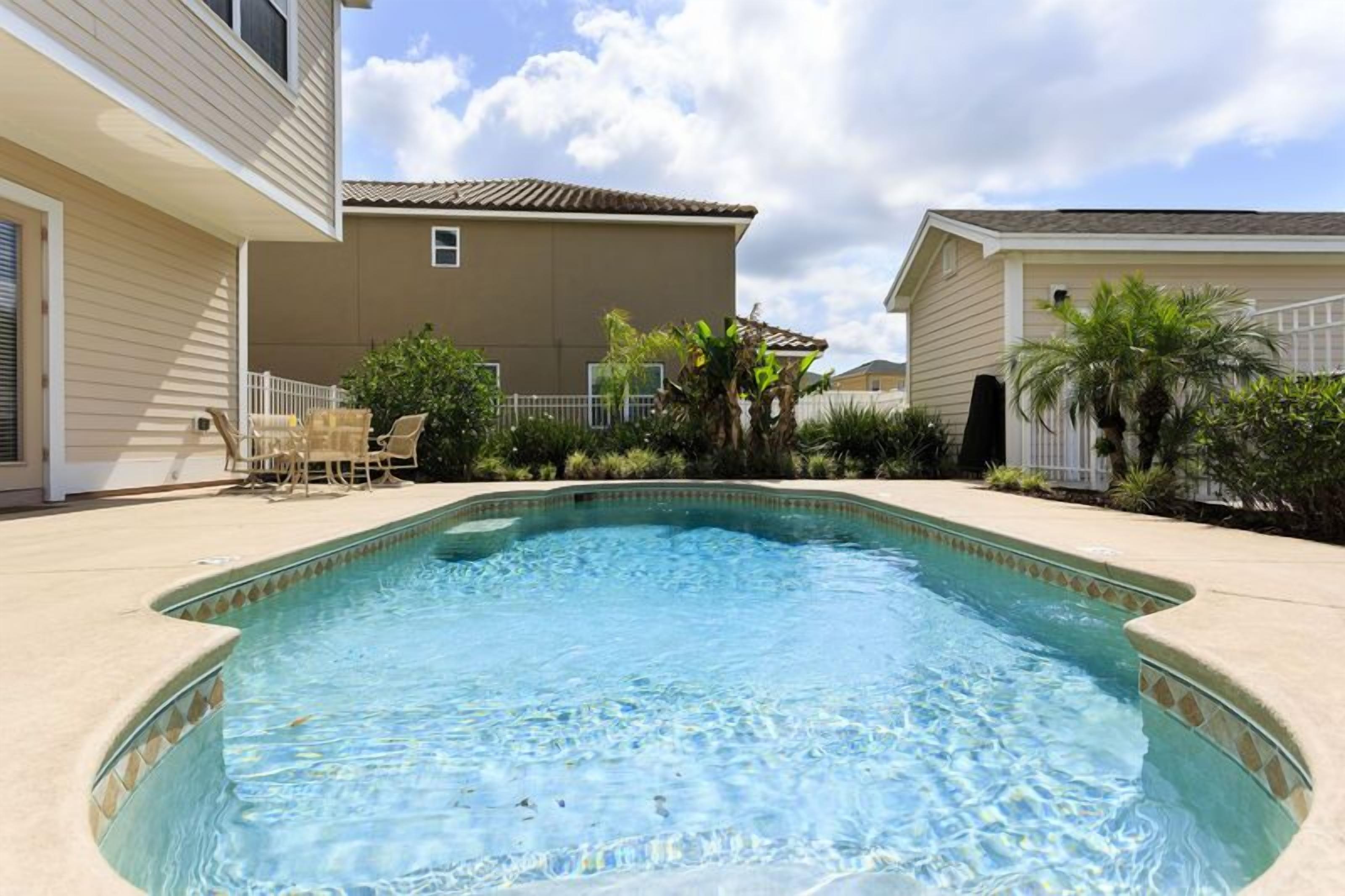 A swimming pool with a tiled edge, surrounded by a beige deck.