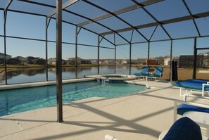Una piscina cubierta al aire libre con sillas de descanso y vistas a un lago y casas.