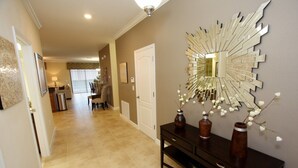 A hallway with a dark wooden console table, a decorative mirror, and a door.