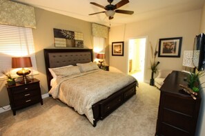 A bedroom with a bed, nightstands, a dresser, a ceiling fan, and artwork on the walls. - Ov4182 - Champions Gate Resort - 8 Bed 5 Baths Villa (Davenport)