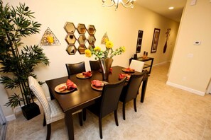 A dining area with a dark wooden table, six chairs, and a vase with yellow flowers.