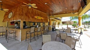 An outdoor bar area with thatched roof, wooden ceiling, and multiple seating arrangements.