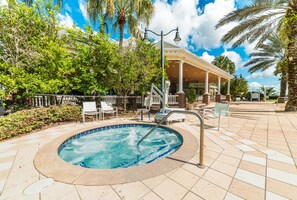 Une piscine dotée d’une terrasse carrelée, entourée de palmiers et agrémentée d’un pavillon couvert.
