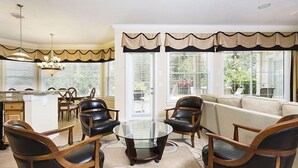 Un salón amplio con una mesa de centro de vidrio, sillones de cuero y un sofá color beige.