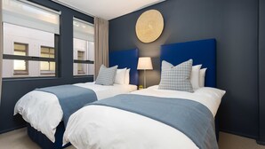 A hotel room with two beds, a large round wall decoration, and a window with curtains. - Fountain Suites 1001 (Cape Town)