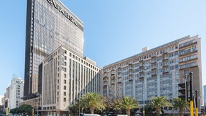 A modern high-rise building with a prominent 'AXA' sign, surrounded by palm trees and other urban buildings. - Fountain Suites 1001 (Cape Town)