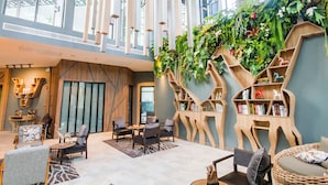 Un vestíbul ampli amb sostres alts, mobles moderns i una biblioteca de fusta amb forma d'arbre, plena de llibres i objectes decoratius.