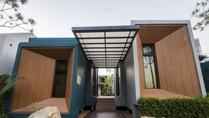 Un edifici modern amb terrassa de fusta, barana metàl·lica i vista clara de l'interior.