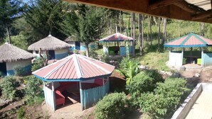 A rustic outdoor area with thatched-roof huts and a small structure with a metal roof. - Maverick Camp Rondavels and Homestay (Aberdare National Park)