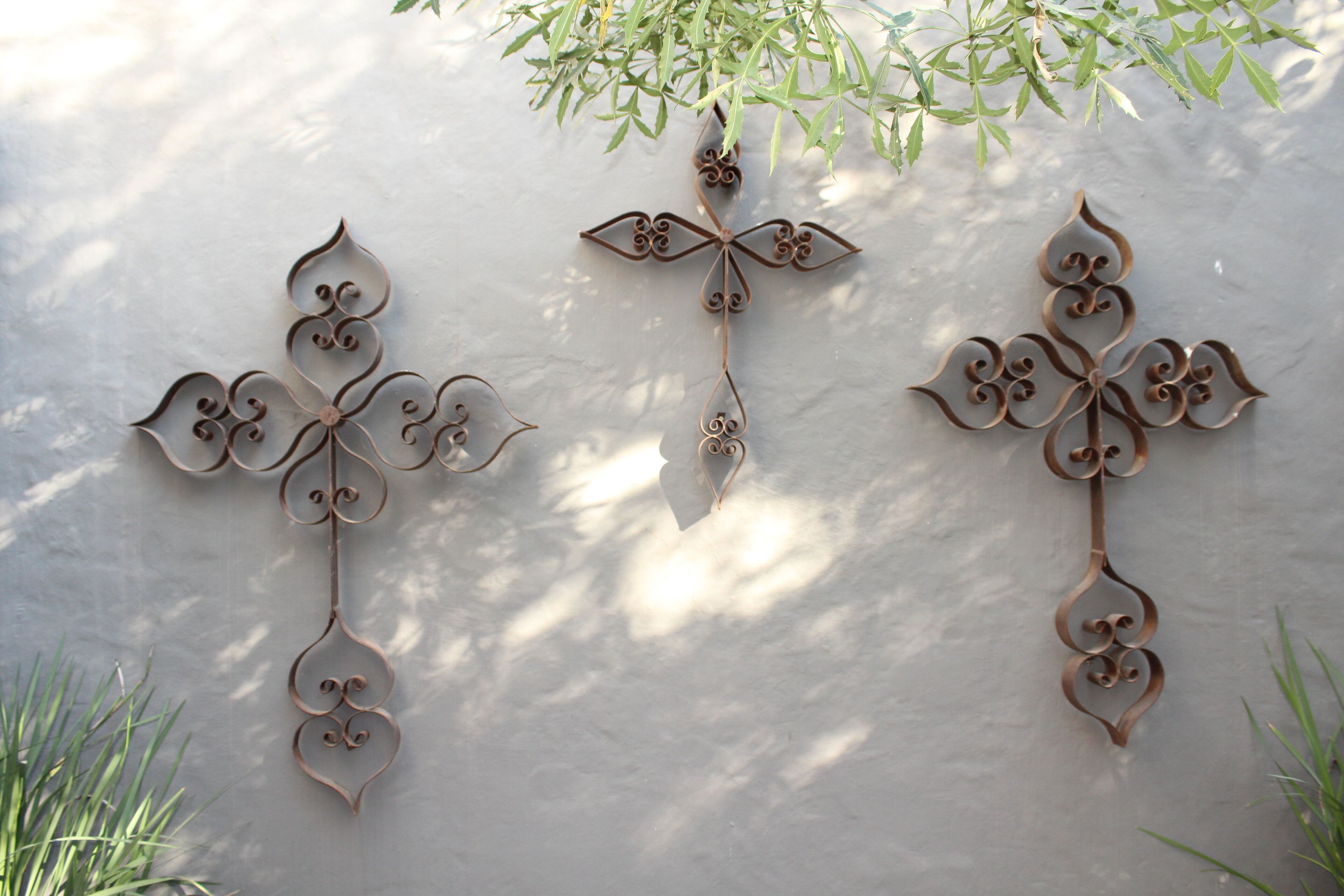 Drie decoratieve metalen wanddecoraties met ingewikkelde patronen.