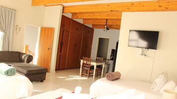 A hotel room with a bed, a sofa, a TV mounted on the wall, and a wooden ceiling.