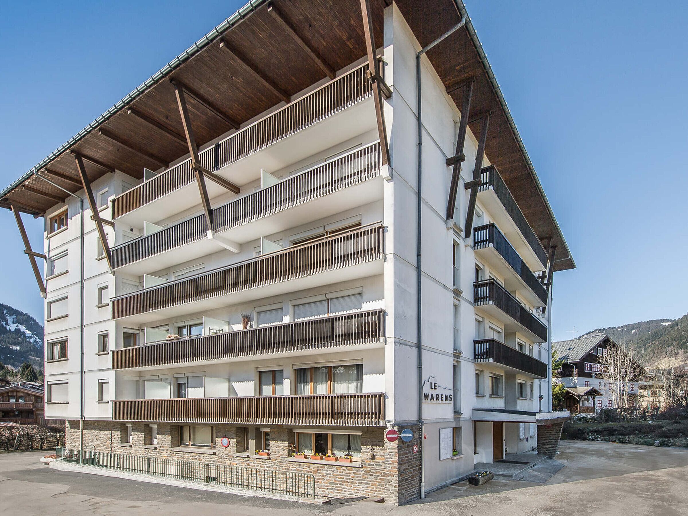 A multi-story hotel with balconies, a stone facade, and a sign reading "LE WARENS".