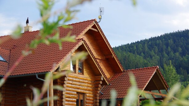 A wooden cabin with a red-tiled roof, a chimney, and a window. - Agroturystyka Dom z Bali (Miłków)