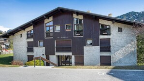 A modern building with a stone facade and multiple windows, featuring a ramp and a small staircase leading to the entrance. - 2-room apartment in Megève, south-facing balcony, near center (Megève)