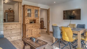 A dining area with a wooden table, chairs, and a cabinet. - 2-room apartment in Megève, south-facing balcony, near center (Megève)
