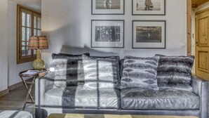 A living room with a leather sofa, a lamp, and four framed pictures on the wall.