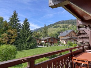 A wooden chalet with a balcony overlooking a green landscape and a mountain in the background. - 3-Room Apartment in Megève with Balcony and Garage (Megève)