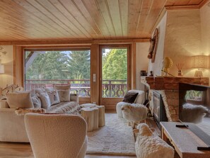 Ein gemütliches Wohnzimmer mit Kamin, einer Sofagarnitur und Blick ins Freie.