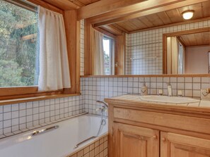 Ein Badezimmer aus Holz mit einer Badewanne, einem Waschbecken und einem großen Spiegel.