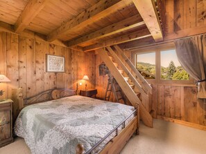 Quarto de cabana de madeira com uma cama, janela com vista e escada.