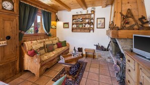 Un intérieur chaleureux en bois, avec un canapé, une cheminée et une horloge au mur.