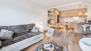 A modern living room with a sofa, a coffee table, and a dining area with chairs and a table.